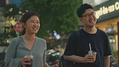 Founders, Suji and Han, are walking with drinks in their hands along a dimly lit sidewalk.