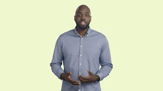 A portrait of a man in a light blue buton-down shirt speaking against a neutral, off-white background.