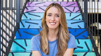 Founder Andrea Barber smiles in front of a colorful staricase