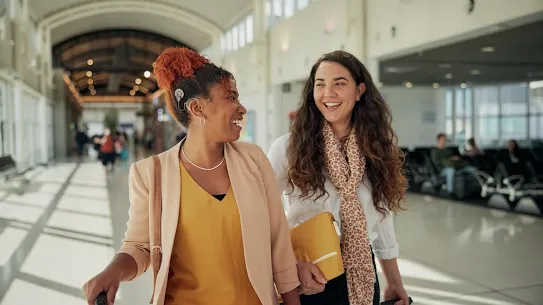 Woman with hearing aid device walking next to another woman in an airport