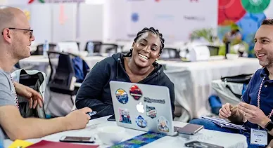 A group of people having a discussion with open laptops in front of them.
