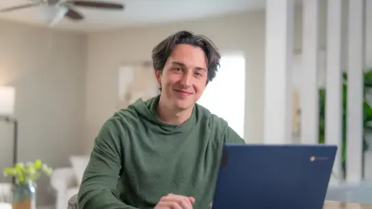 student with a laptop smiling at the camera