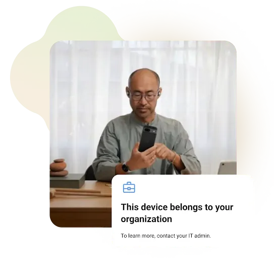 Man using a smartphone while seated at a desk. The setting appears to be a home office or workspace. A message on the screen reads, 