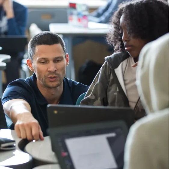 A photograph of a teacher and a student in a classroom setting