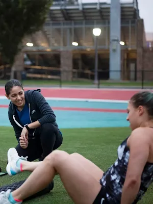 Two women in tracksuits are seated in the garden.