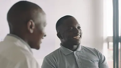 Founder, Gerald Otim, smiles at a table with colleagues.