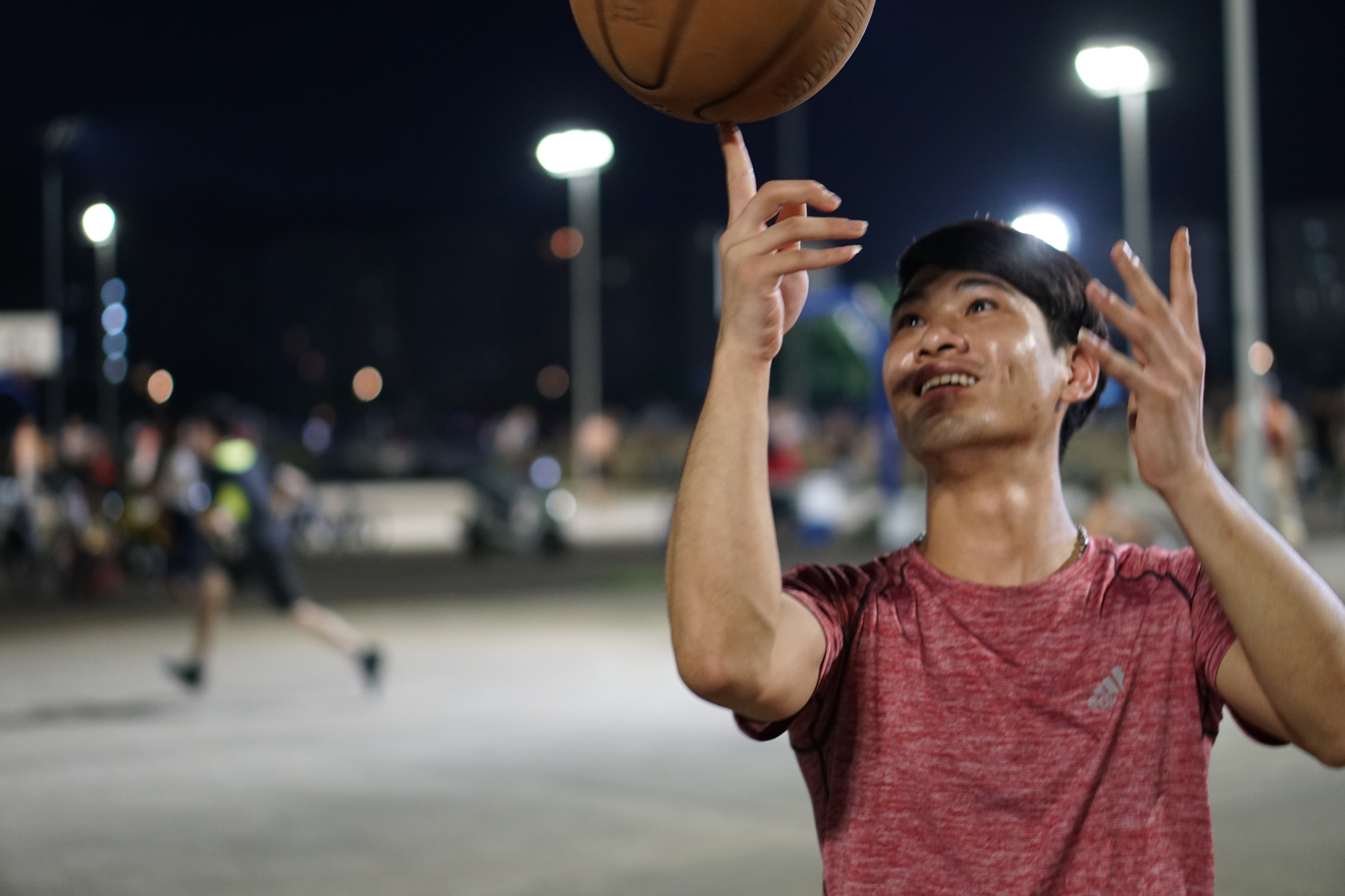 A person smiling and spinning a basketball on one finger.