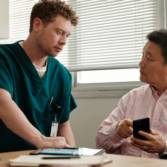 A doctor speaks with a man that's pointing at his phone
