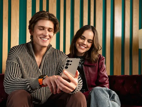 Man and woman sitting together looking at Android phone