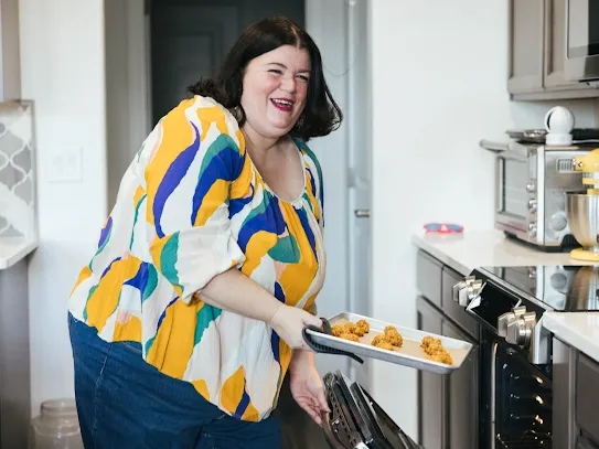 Tammilee putting a tray in the oven.