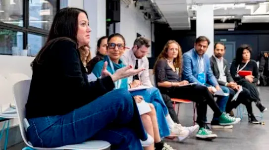 A women talking something and others listening and looking at her.