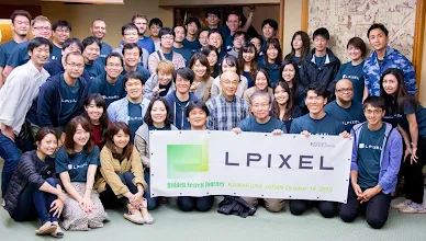 The team of LPixel surrounds a banner revealing their company’s name.