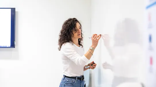 Someone writing on a whiteboard in a conference room. 