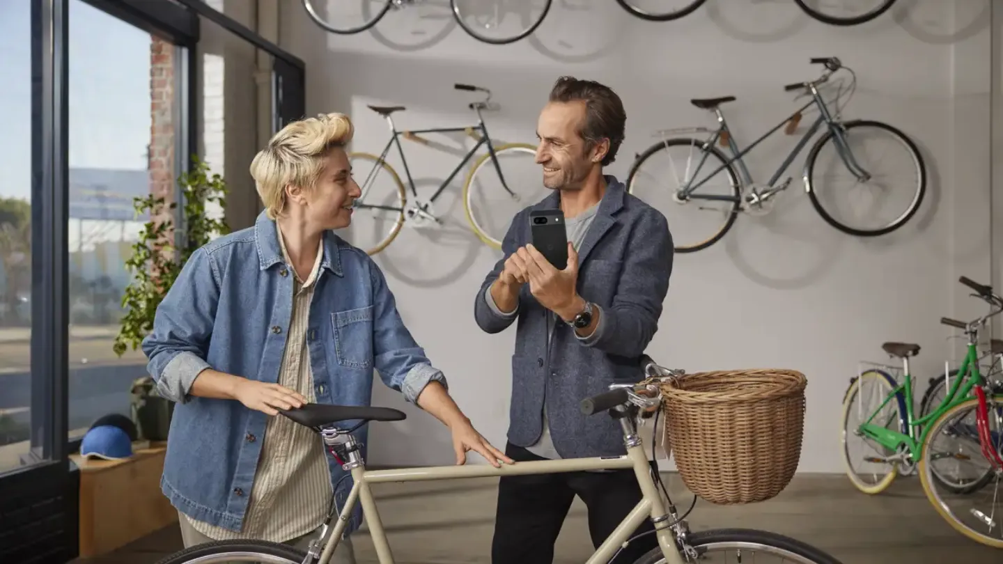 Homme tenant un téléphone Android, discutant avec une femme dans un magasin de vélos
