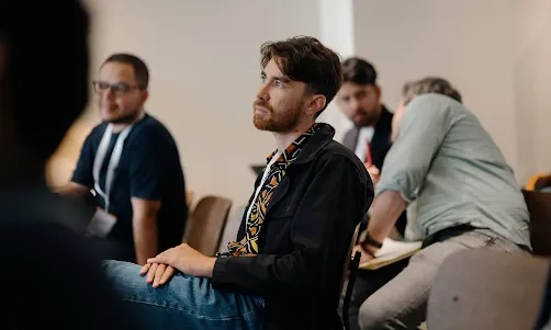 A person in the audience at an event giving their full attention to the speaker.