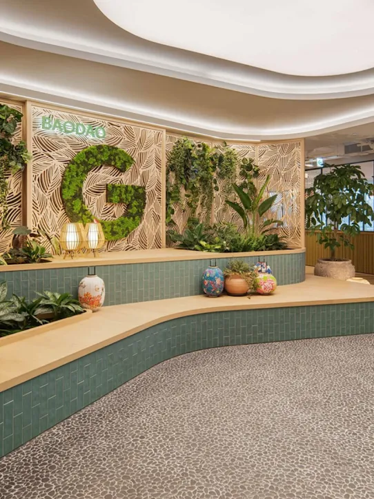 An office space with the “G” logo in green and various plants.