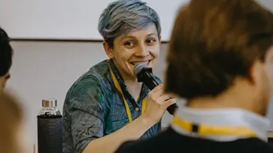 Tina Bychkova, Head of Digital Marketing, is speaking at a conference with colleagues.