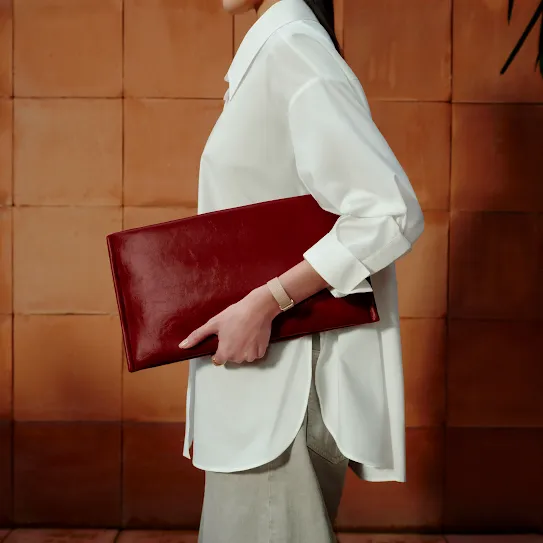A person holding a large clutch and wearing a fitness tracker