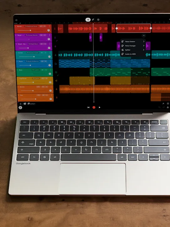 Una laptop Chromebook y un teléfono Android uno al lado del otro sobre un escritorio de madera, ambos con una app de producción musical.