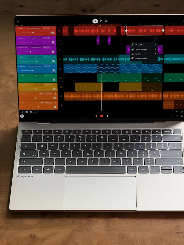 Una laptop Googlebook y un teléfono Android uno al lado del otro sobre un escritorio de madera, ambos con una app de producción musical.
