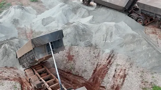 Two construction trucks crush rocks in a gravel pit