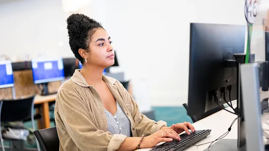 A woman typing at a computer in a computer lab