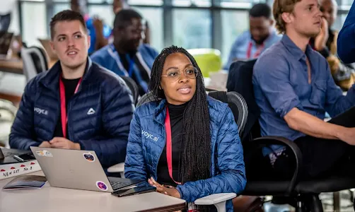Man and women siting in conference room and looking towards someone.