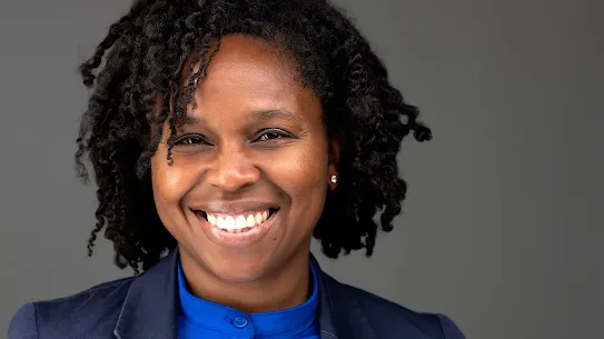 Headshot of Tina Williams-Koroma, founder of CyDeploy, smiling and wearing a blue blazer against a grey background.