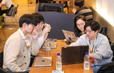 A group of four participants discussing while laptop infront of them