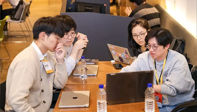 A group of four participants discussing while laptop infront of them