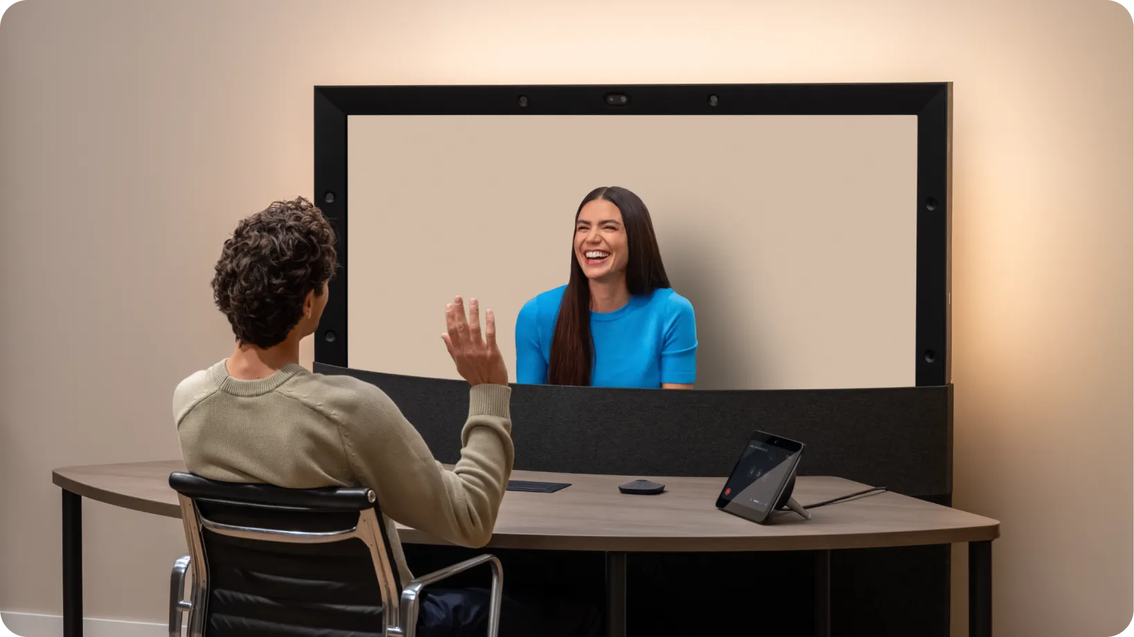A carousel of images and videos shows the evolution of Google Beam devices over time.
Wide-angle of people conversing expressively during a Google Beam meeting.
