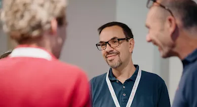 Three peoples are smiling and engaged in conversation.
