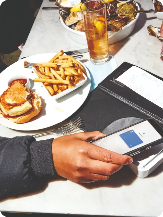 Half eaten hamburger and fries next to an open check at a restaurant