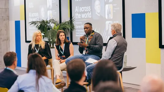 Four panelists seated on stage speaking to an audience during an "AI across the world" panel discussion.