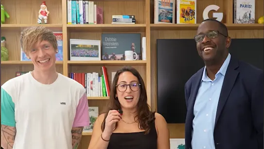 Three people stand in a school library setting