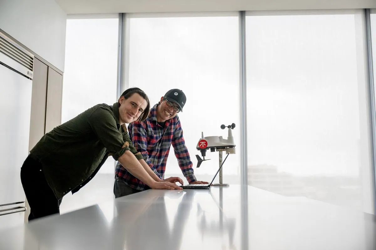 Two men working on a laptop and a machine.