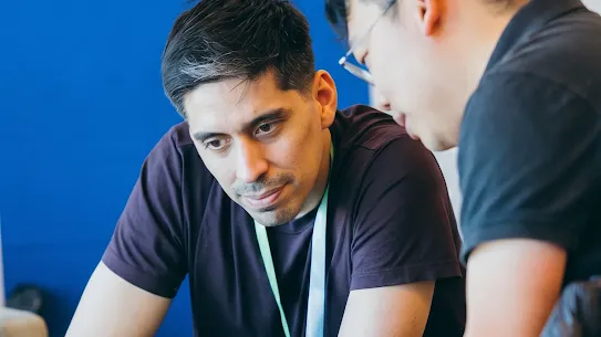 Two men collaborating while looking at a laptop screen during a Google for Startups forum.