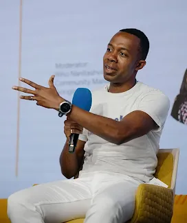 One person on stage, holding microphones and speaking at the event.