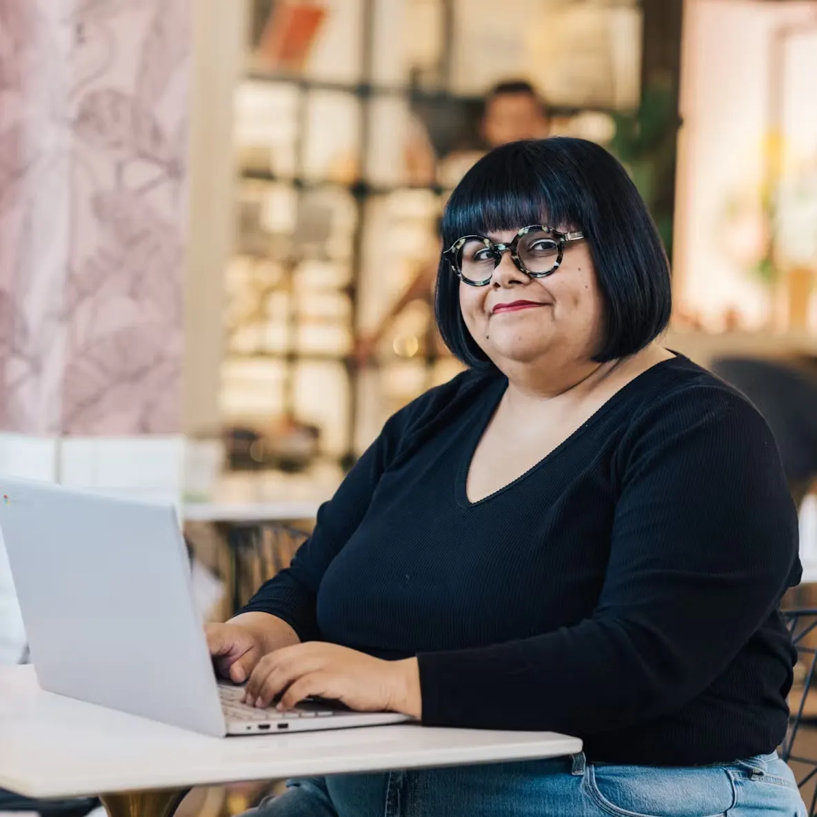 A person sitting at a cafe, doing work on a laptop