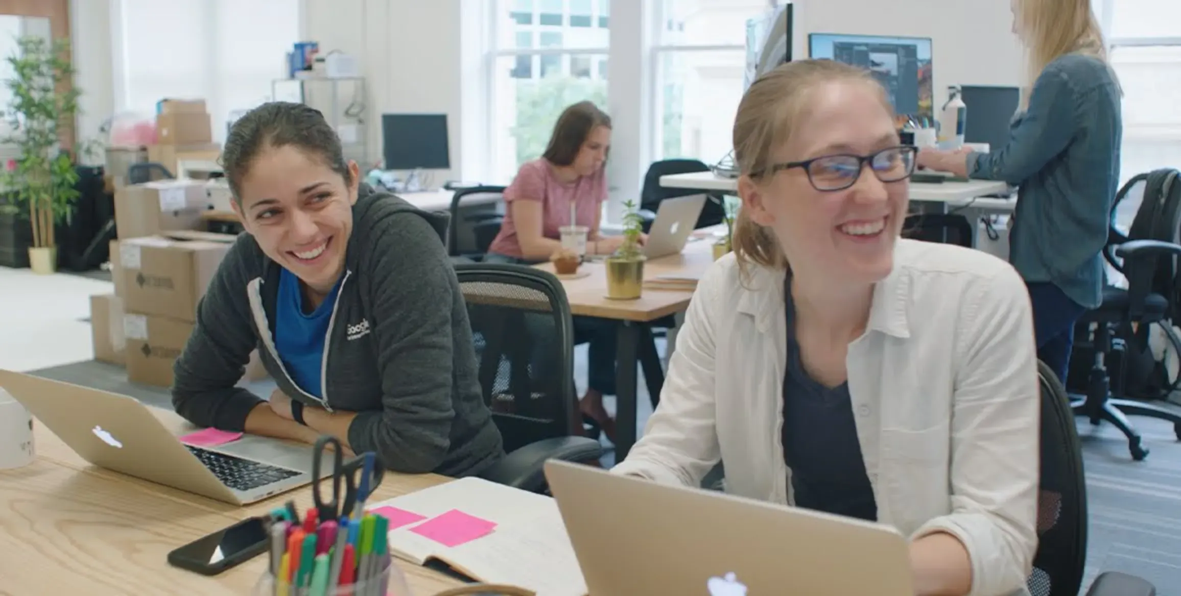 Founders Ivonna Dumanyan and Gabrielle Levac are sitting side by side at a desk during a meeting smiling.
