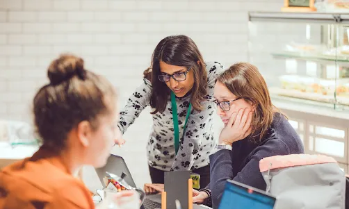 2 Women wearing spects looking into laptop.