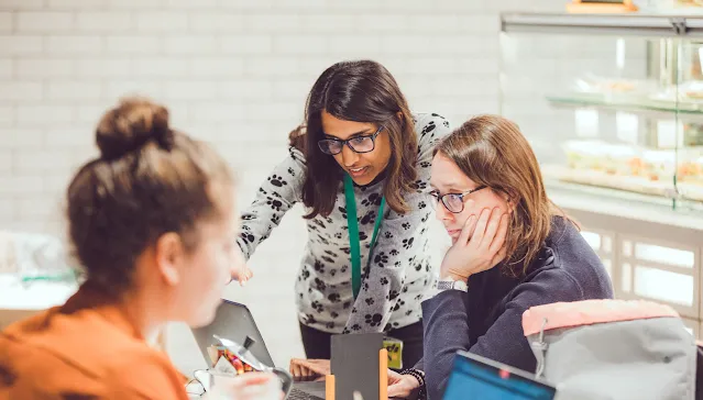 2 Women wearing spects looking into laptop.