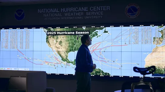 A person standing in front of a large digital display at the National Hurricane Center.
