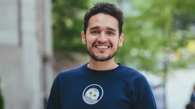 Founder, Jose, smiles in front of a tree lined street.