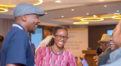 A woman wearing glasses smiles pleasantly while standing with a group of people.