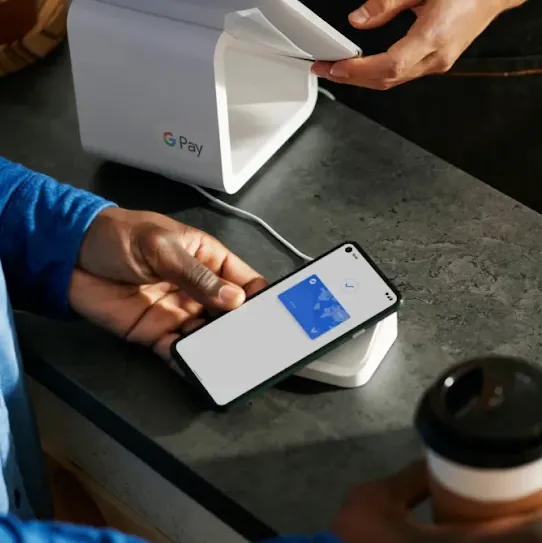 someone using Google Pay to pay for their burger and fries at a restaurant