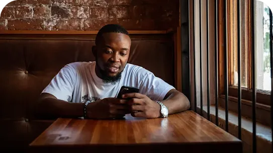 Man sitting in cafe looking at his phone.