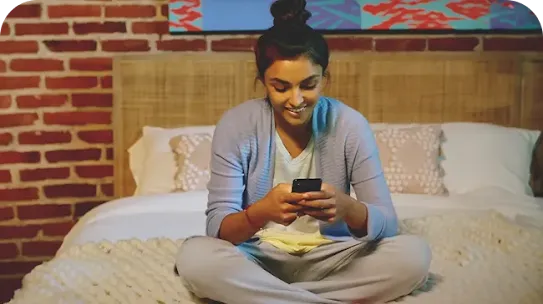 Woman sitting on bed with Android phone