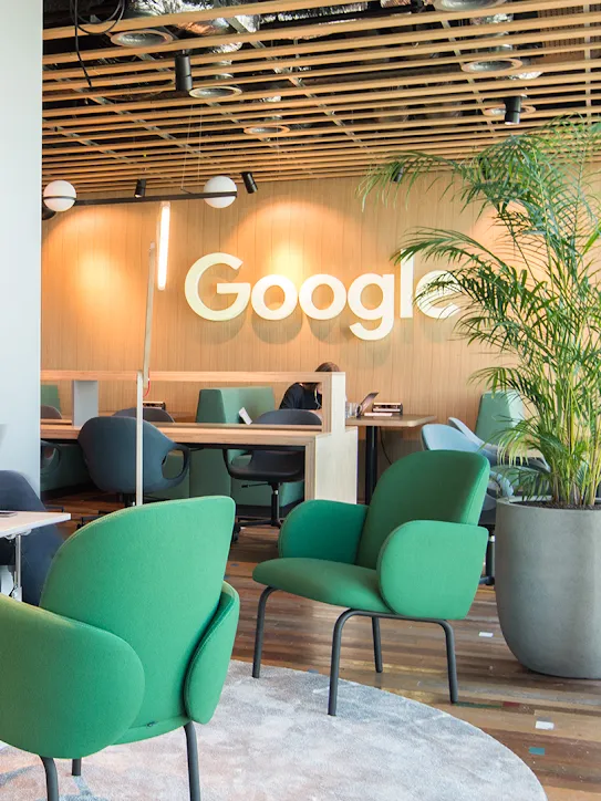 في مساحة عمل مُبتكَرة، يجلس شخصان مع ظهور شعار Google في الخلفية