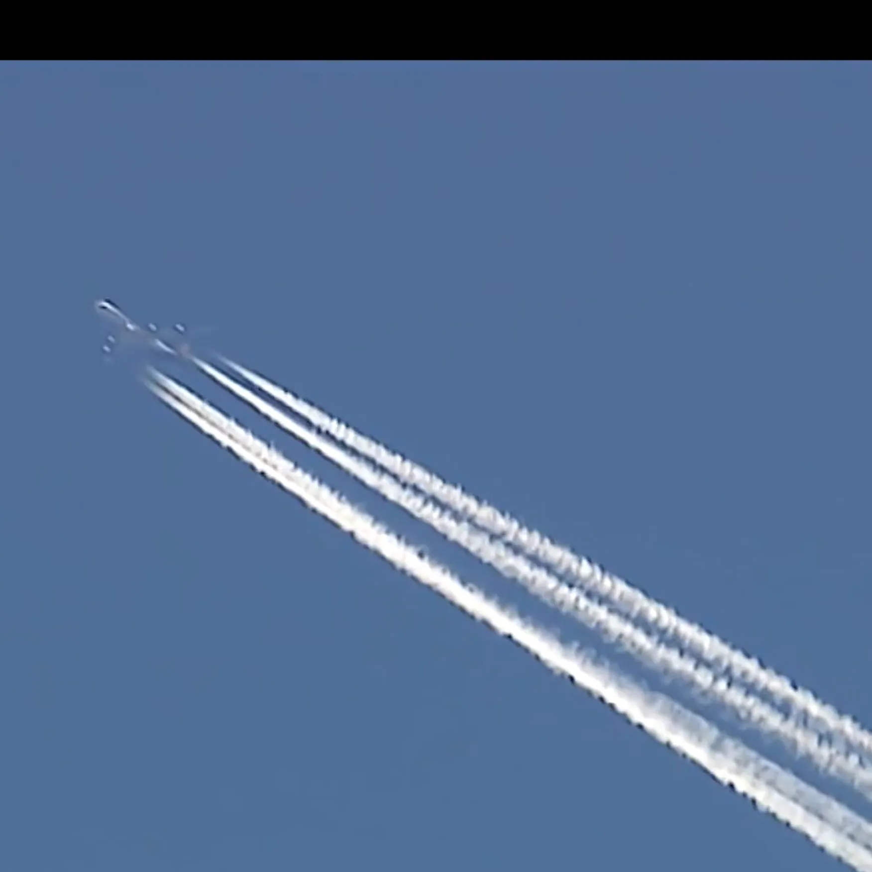 Airplain contrails are seen against a cloudless blue sky.